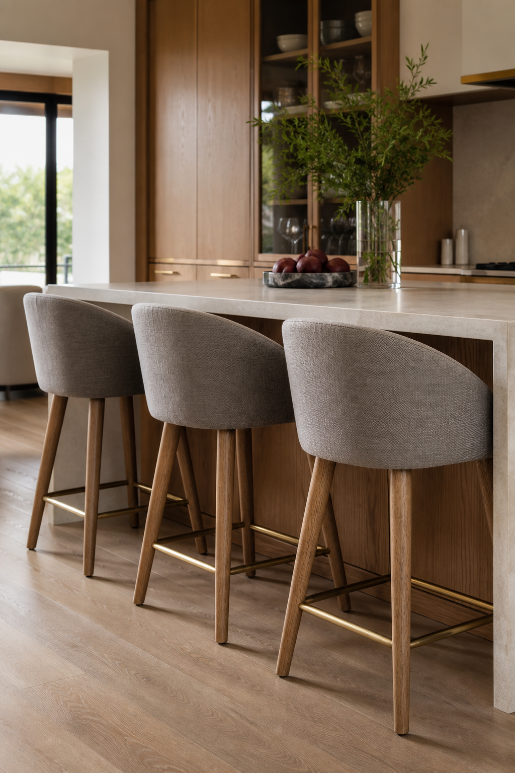 Modern kitchen island with comfortable upholstered counter stools and warm stone finishes