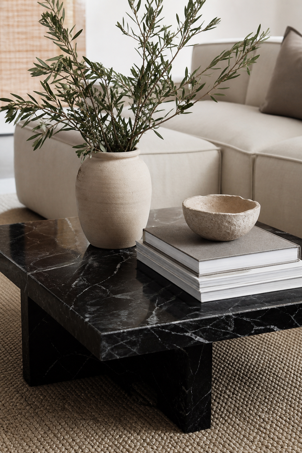 Luxury coffee table styled with ceramic vessel, art books, stone bowl, and fresh branches